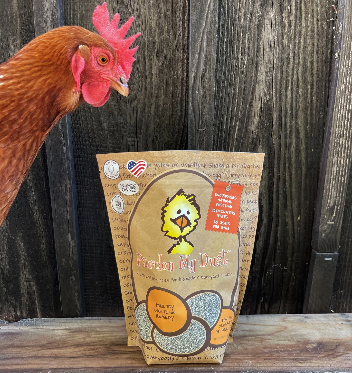 Wooden background with a handsome rooster standing above a package of Pardon My Dust. Treats for Chickens Organic Ingredients Pet Care Poultry Care Pardon My Dust Backyard Chicken Parents Organic Ingredients Treats for Chickens treats, supplements, herbal nesting box blend, + poultry care. Est 2009 by Dawn in Sonoma County, California, USA. TFC.